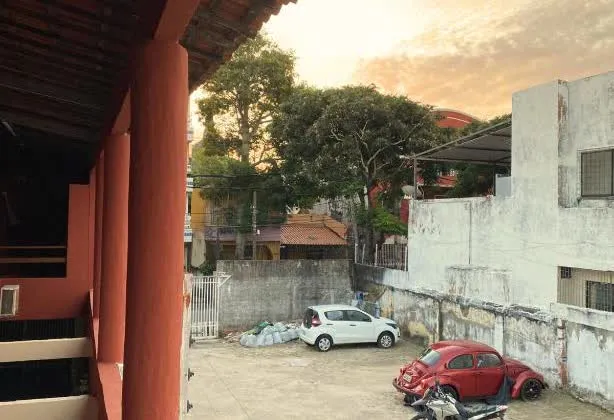 O pátio visto da varanda no fim da tarde, com carros e moto estacionados